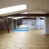 Attic yoga studio with wooden beams, multiple skylights, and blue yoga mats on light wood flooring.
