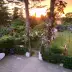 Sunset over a well-kept garden with pines, blooming roses, and a surfboard on paving stones, ideal for family parties or group trips.