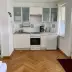 Kitchen area with white cabinets, stove, oven, and refrigerator; adjacent bathroom with shower and bathtub, wooden floor in herringbone pattern.