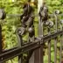 Detalle de un barandilla met&aacute;lica oscura con decoraciones florales y espirales sobre fondo verde